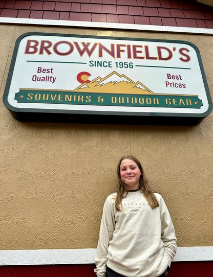 Person standing in front of a sign for Brownfield's Souvenirs & Outdoor Gear.